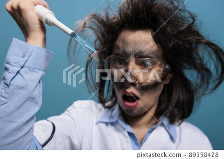 Crazy mad chemistry reasearcher with dirty face and messy hair experimenting with unknown compounds. Lunatic chemist looking shocked at professional pipette filled with experimental liquid substance. Crazy mad chemistry reasearcher with dirty face and messy hair experimenting with unknown compounds. Lunatic chemist looking shocked at professional pipette filled with experimental liquid substance. 89158428
