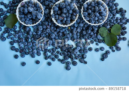 Flat lay of fresh organic juicy blueberries in a bowl on blue background 89158718