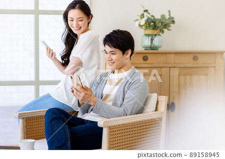 A couple operating a smartphone while relaxing at home 89158945