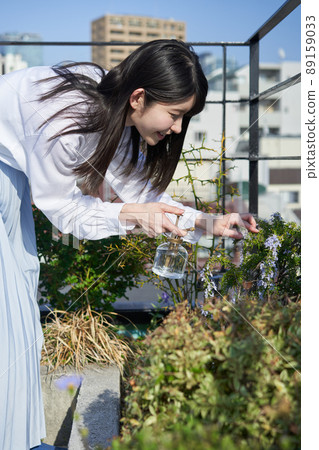 Woman spraying water on plants Woman spraying water on plants 89159033