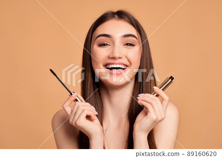 woman hold mascara isolated on beige background woman hold mascara isolated on beige background 89160620