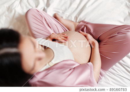 Pregnant woman holding her hands on her belly 89160783
