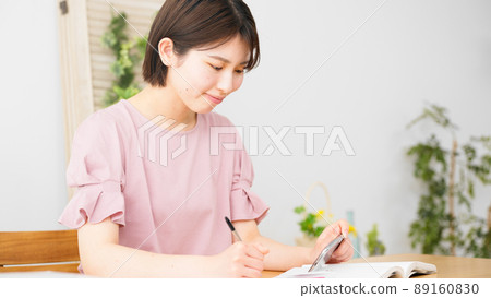 A woman studying while watching a smartphone 89160830