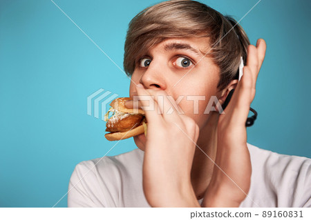 Very hungry young man holding tasty hamburger 89160831
