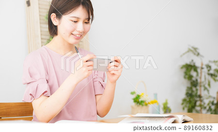 A woman studying while watching a smartphone 89160832