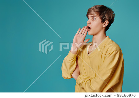 guy in yellow sweater holds hand near mouth call somebody guy in yellow sweater holds hand near mouth call somebody 89160976