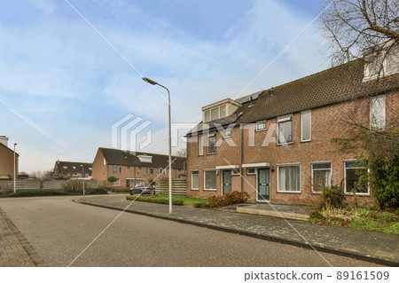 A small residential brick house with a lawn in front of the house and a driveway A small residential brick house with a lawn in front of the house and a driveway 89161509