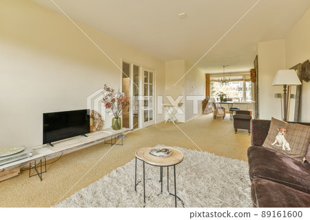 The interior of a spacious living room with a dining area, a panoramic window and lots of house plants The interior of a spacious living room with a dining area, a panoramic window and lots of house plants 89161600