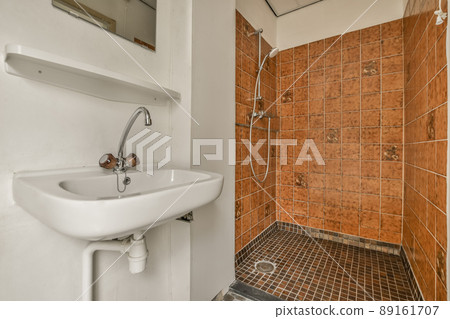 A bathroom in a cozy house with a sink under the mirror and a shower next to it A bathroom in a cozy house with a sink under the mirror and a shower next to it 89161707
