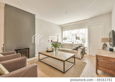 A small living room with a fireplace next to a sofa, a carpet on the floor and a vase with plants A small living room with a fireplace next to a sofa, a carpet on the floor and a vase with plants 89161781