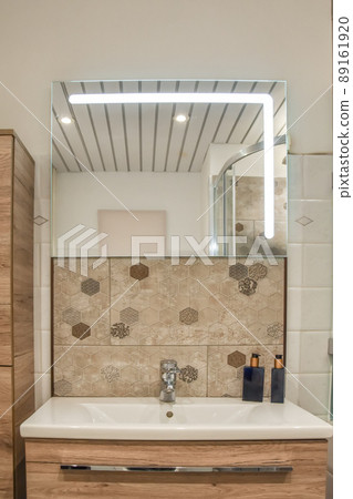 Ceramic sink under the mirror with bathroom accessories and drawers under it in a modern house 89161920