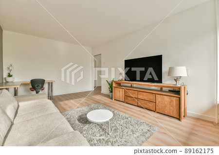 A spacious living room with a terry carpet on the floor and a sofa in front of the TV in a modern apartment A spacious living room with a terry carpet on the floor and a sofa in front of the TV in a modern apartment 89162175
