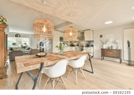 An open space with a dining area and a small corner kitchen in white in a cozy house 89162195