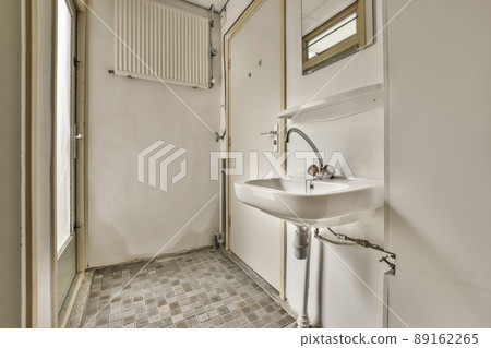 A bathroom in a cozy house with a sink under the mirror and a door out next to it A bathroom in a cozy house with a sink under the mirror and a door out next to it 89162265