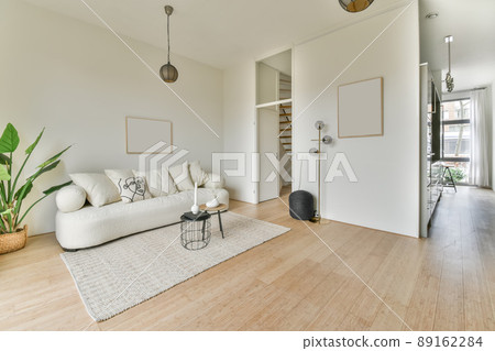 A spacious, bright living room with a large white sofa on the carpet in a cozy house A spacious, bright living room with a large white sofa on the carpet in a cozy house 89162284