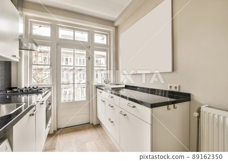 Small white kitchen with stylish tiles, black countertop and sink with faucet. Scandinavian interior of a room in an apartment. Small white kitchen with stylish tiles, black countertop and sink with faucet. Scandinavian interior of a room in an apartment. 89162350