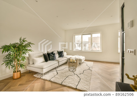 Cozy living room in white tones with a large sofa on the carpet in a modern house Cozy living room in white tones with a large sofa on the carpet in a modern house 89162506