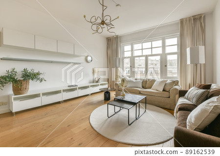 Living room with comfortable sofas on the parquet floor and access to the balcony in a modern house 89162539