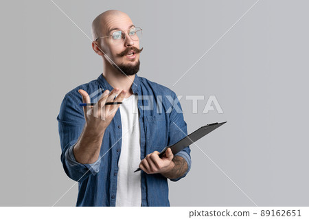 Image of handsome balded with musctache and beard man wearing casual clothes holding clipboard isolated over white background. Image of handsome balded with musctache and beard man wearing casual clothes holding clipboard isolated over white background. 89162651
