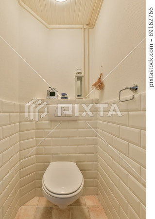 Bathroom interior with a hinged toilet surrounded by white tiles Bathroom interior with a hinged toilet surrounded by white tiles 89162766