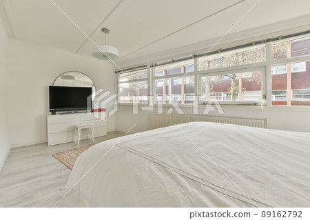 A small bedroom with a double bed in a white design and a TV opposite in a modern house A small bedroom with a double bed in a white design and a TV opposite in a modern house 89162792