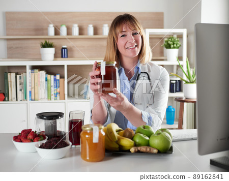 Female nutritionist holding honey in office studio 89162841