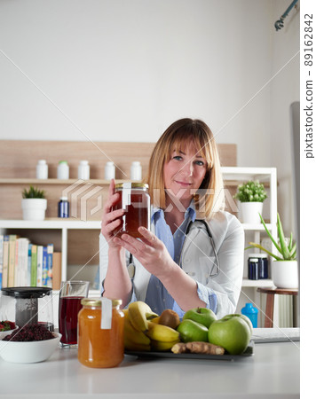 Female nutritionist holding honey in office studio Female nutritionist holding honey in office studio 89162842