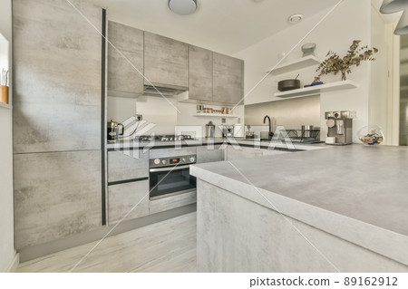 The interior of the kitchen in a gray design with modern equipment in a cozy house The interior of the kitchen in a gray design with modern equipment in a cozy house 89162912
