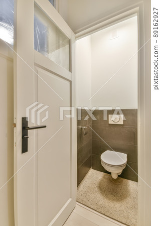 Toilet with dark tiled walls and marble floor in a cozy house 89162927