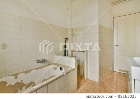 A small, old-fashioned bathroom with a marble-style tile bathtub and sink A small, old-fashioned bathroom with a marble-style tile bathtub and sink 89163023