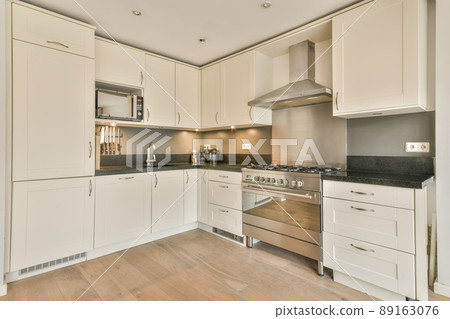 A small corner kitchen in white on a parquet floor in a cozy house A small corner kitchen in white on a parquet floor in a cozy house 89163076