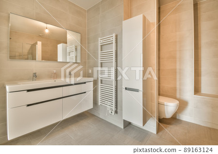 Spacious bathroom with beige tiles, double sink and toilet in a modern house 89163124