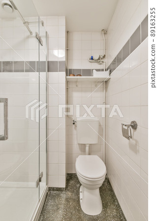 The interior of the bathroom made of white tiles with a glazed shower and a toilet The interior of the bathroom made of white tiles with a glazed shower and a toilet 89163255