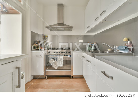 Kitchen interior in white with modern appliances in a cozy spacious apartment Kitchen interior in white with modern appliances in a cozy spacious apartment 89163257