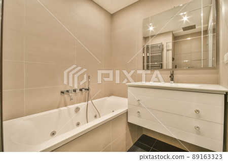 Bathroom in beige design with a large sink and ceramic bathtub in a modern house Bathroom in beige design with a large sink and ceramic bathtub in a modern house 89163323