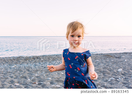 Little cute child girl playing on the seashore in summer 89163345