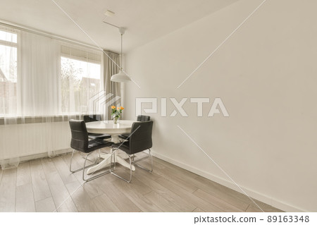 Interior of a dining area in white near to the window in a cozy house 89163348