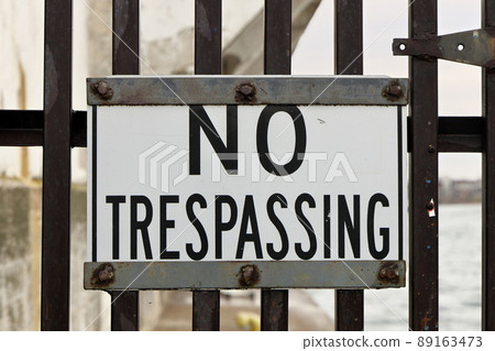 Close up of No Trespassing Sign Posted on Industrial Metal Gate 89163473