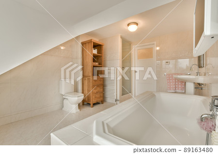 Spacious bathroom with white tiles, sink, bathtub, toilet in a modern house 89163480
