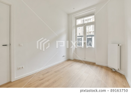 The interior of a small room in white with parquet floor and access to the street through the door The interior of a small room in white with parquet floor and access to the street through the door 89163750