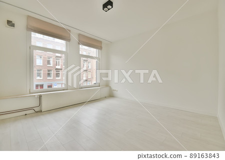 Spacious empty room with a large window and a parquet floor in a cozy house Spacious empty room with a large window and a parquet floor in a cozy house 89163843