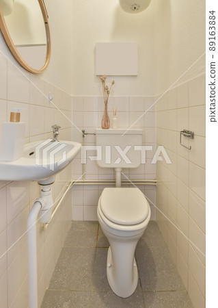 Bathroom interior in white tones with a toilet and ceramic sink under the mirror Bathroom interior in white tones with a toilet and ceramic sink under the mirror 89163884