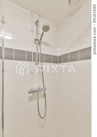 The interior of the bathroom made of white tiles with a shower in a modern house 89163888