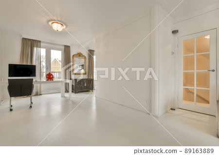 Spacious workspace in white with a computer next to a big mirror in a modern house 89163889