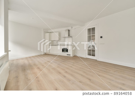 Large room in an empty new house with a corner kitchen in a minimalist style, made in white Large room in an empty new house with a corner kitchen in a minimalist style, made in white 89164058