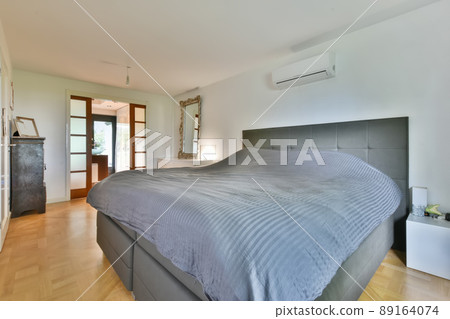 Spacious cozy bedroom with a large bed and a large mirror in a modern apartment Spacious cozy bedroom with a large bed and a large mirror in a modern apartment 89164074