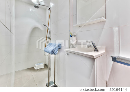 Interior of a white tiled bathroom with shower and sink in a modern house 89164144