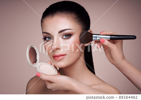 Beautiful woman applies skin tone with brush 89164462