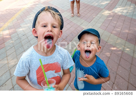 Preschooler and toddler with blue tongues from fruit ice Preschooler and toddler with blue tongues from fruit ice 89165608
