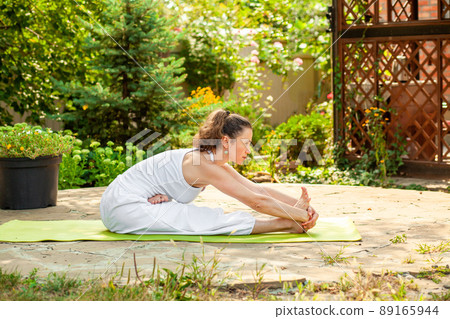 Young woman practices yoga in the garden. Ardha Padma Janushirshasana 89165944